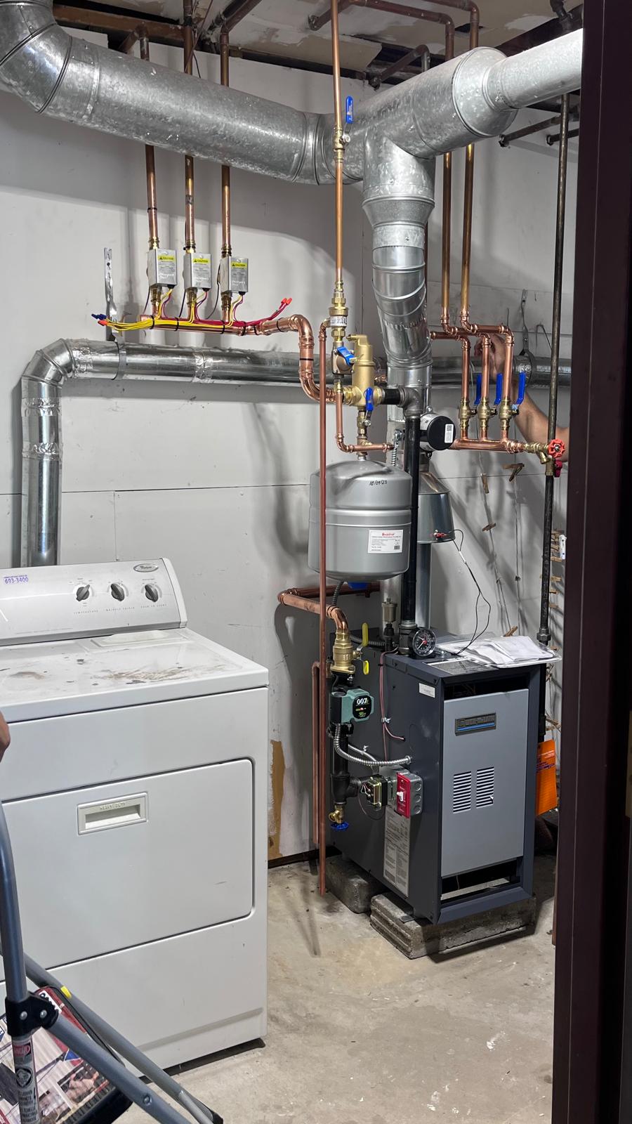 Buderus boiler and copper piping beside laundry equipment