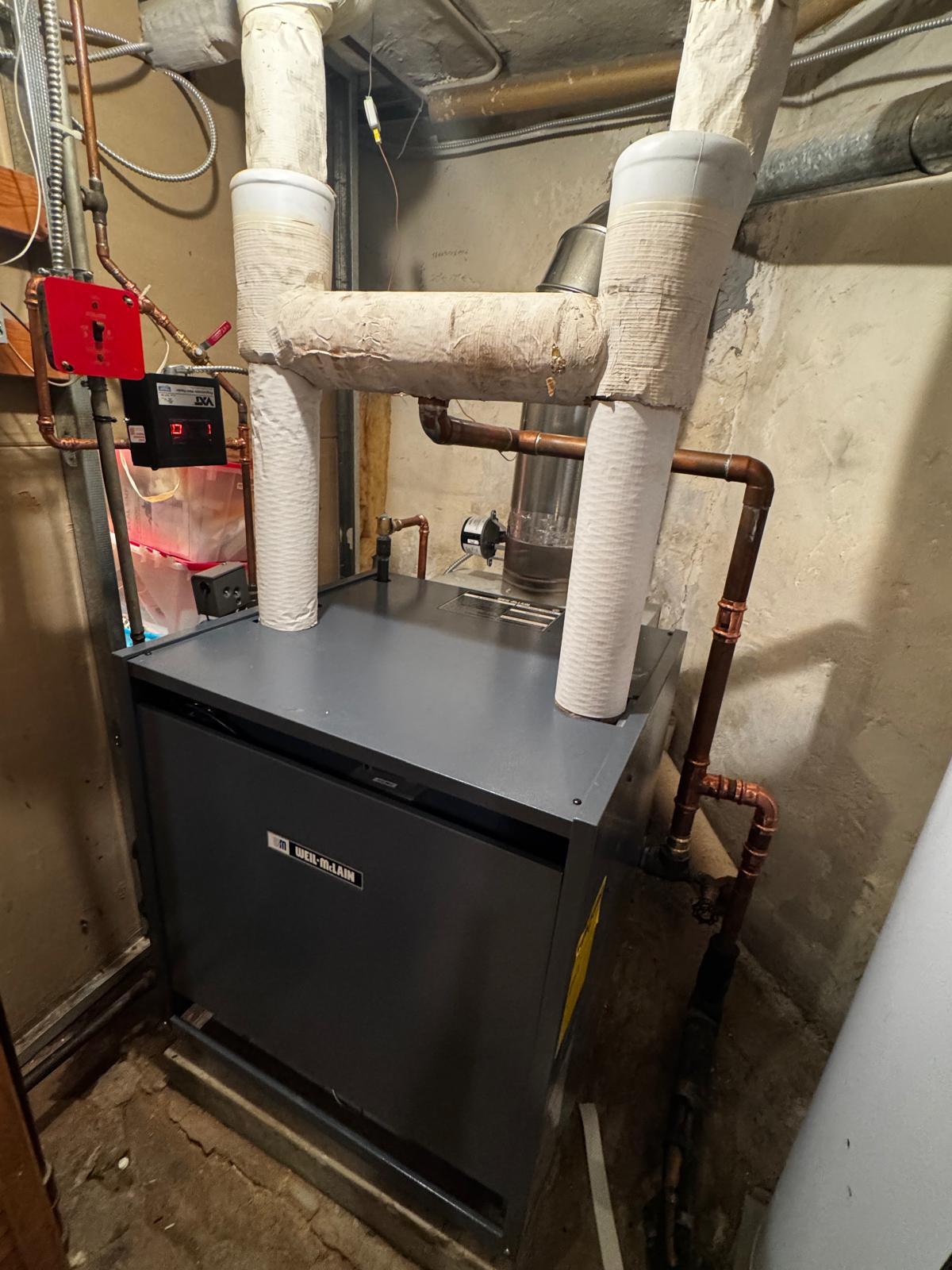 Weil-McLain boiler with insulated vents and copper piping in a mechanical room